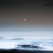 full moon setting over ocean